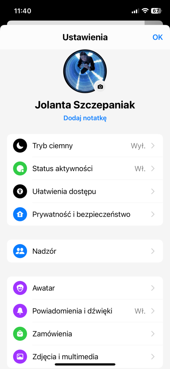 Zrzut ekranu menu ustawień aplikacji z listą opcji takich jak Tryb ciemny, Status aktywności, oraz awatarem użytkowniczki Jolanty Szczepaniak stojącej w przejściu tunelowym i korzystającej z telefonu.