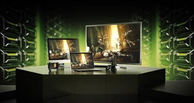 Zestaw urządzeń gamingowych z grafiką z gry na ekranach, w tym monitor, laptop i tablet, na tle ściany z zielonym oświetleniem.