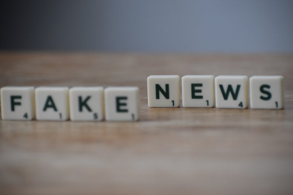 fake newsy - Kostki do gry scrabble układające się w słowa "FAKE NEWS" na drewnianym stole.
