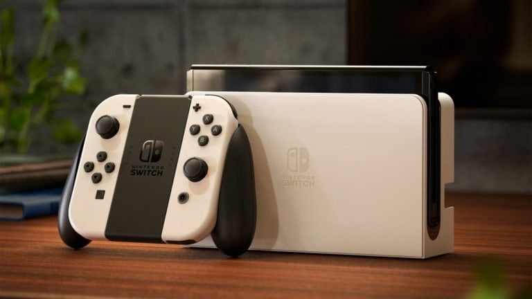 Konsola do gier Nintendo Switch umieszczona na drewnianym blacie, z doczepionymi dwoma kontrolerami Joy-Con po bokach ekranu.