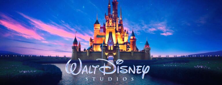 Logo Walt Disney Studios z bajkowym zamkiem na tle kolorowego nieba o zmierzchu.
