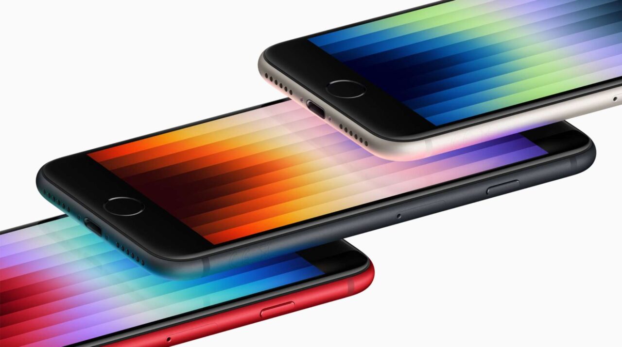 Specyfikacja iPhone'a SE 4 nie jest jeszcze znana. Trzy smartfony ułożone jeden na drugim z kolorowymi tłami na ekranach tworzącymi efekt gradientu.