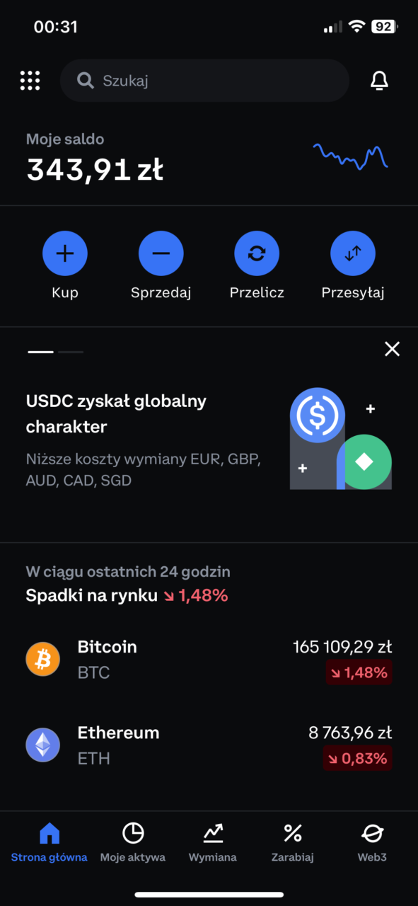Zrzut ekranu aplikacji finansowej pokazujący saldo w PLN, przyciski kupna i sprzedaży, aktualności dotyczące USDC, oraz spadki wartości Bitcoina i Ethereum z ostatnich 24 godzin.