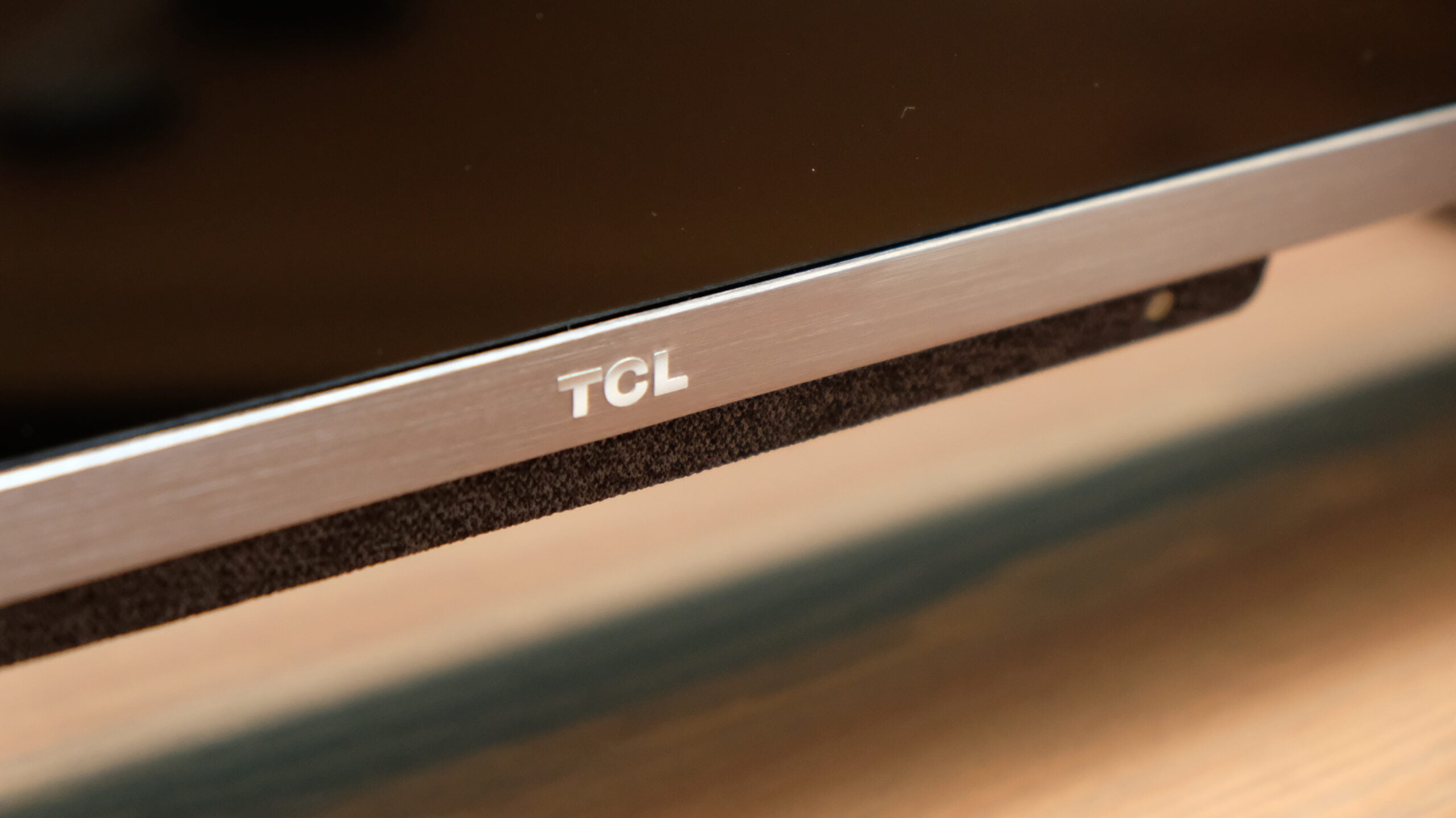Recenzja TCL C728, zdjęcie główne przedstawiające spód telewizora z widocznym logo