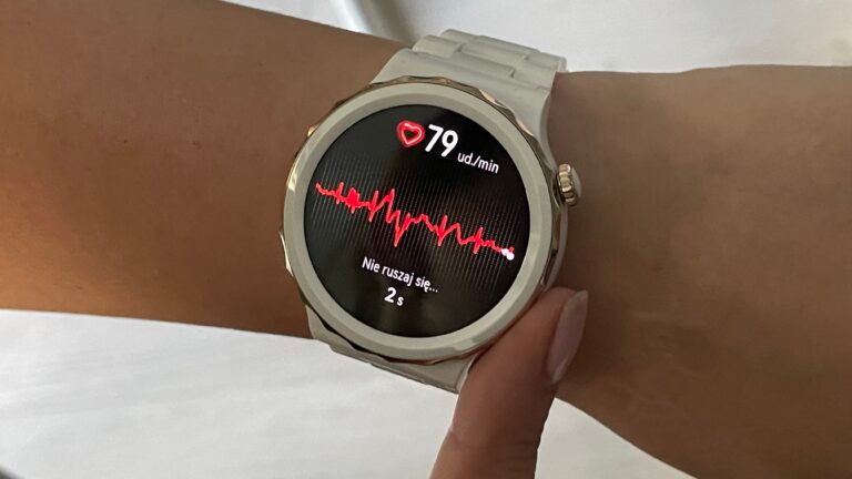 Inteligentny zegarek na nadgarstku wyświetlający tętno 79 uderzeń na minutę oraz elektrokardiogram z napisem "Nie ruszaj się... 2s".