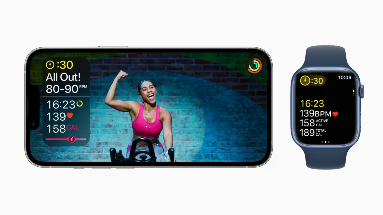 Smartfon i smartwatch wyświetlające aplikację do ćwiczeń z uśmiechniętą kobietą ćwiczącą na tle ceglanej ściany.