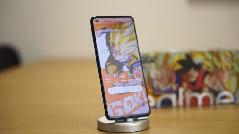 smartfon realme gt neo 3t z włączonym ekranem, stojący na biurku