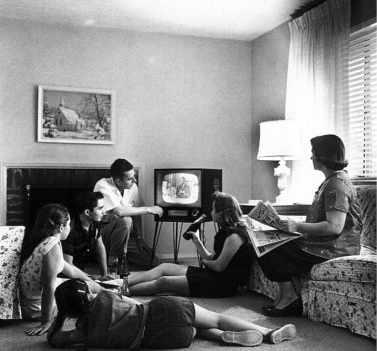 Czarno-białe zdjęcie przedstawiające rodzinę oglądającą telewizję w salonie z lat 50. lub 60. XX wieku. To nie jest przepis na długowieczność