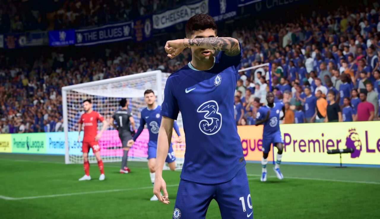 Zrzut ekranu z gry FIFA 23. Piłkarz w niebieskim stroju z numerem 19 świętuje zdobyty gol, zasłaniając dłoniami twarz, w tle widać bramę i kibiców.