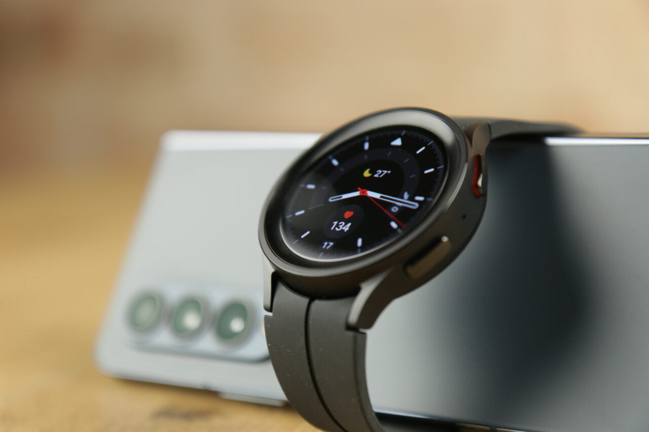 Inteligentny zegarek z okrągłą tarczą wyświetlającą puls i temperaturę, oparty na smartfonie z potrójnym aparatem fotograficznym, z rozmytym tłem.