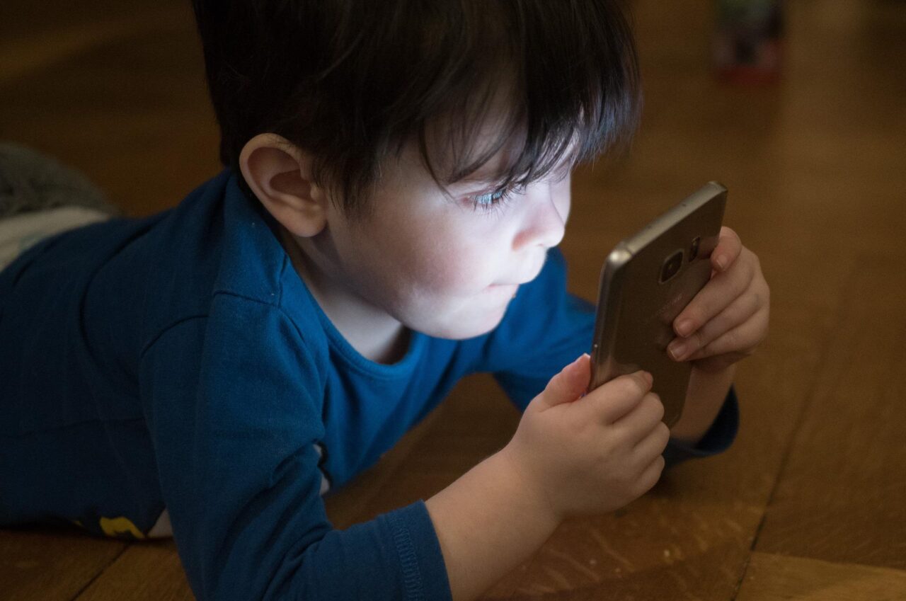 dziecko ze smartfonem, wysoka jasność ekranu, oświetlona twarz