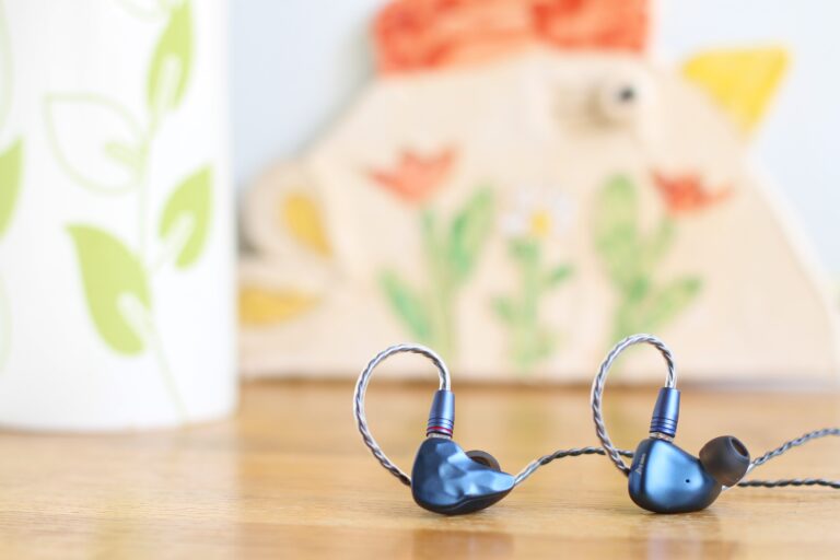 Jakie słuchawki douszne kupić - zdjęcie główne przedstawiające słuchawki dokanałowe Ikko i kolorowe tło