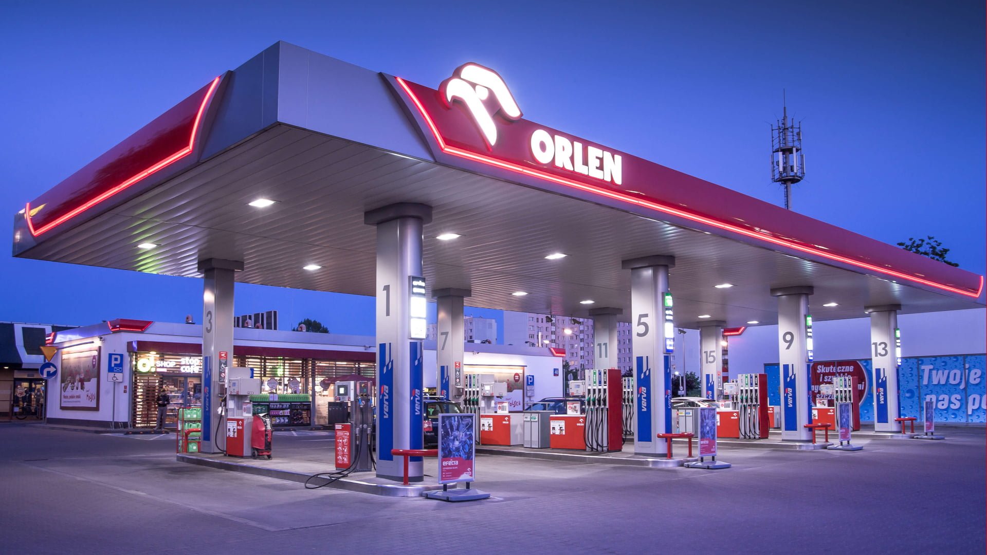 Stacja benzynowa Orlen o zmierzchu, z dystrybutorami paliwa i sklepem.