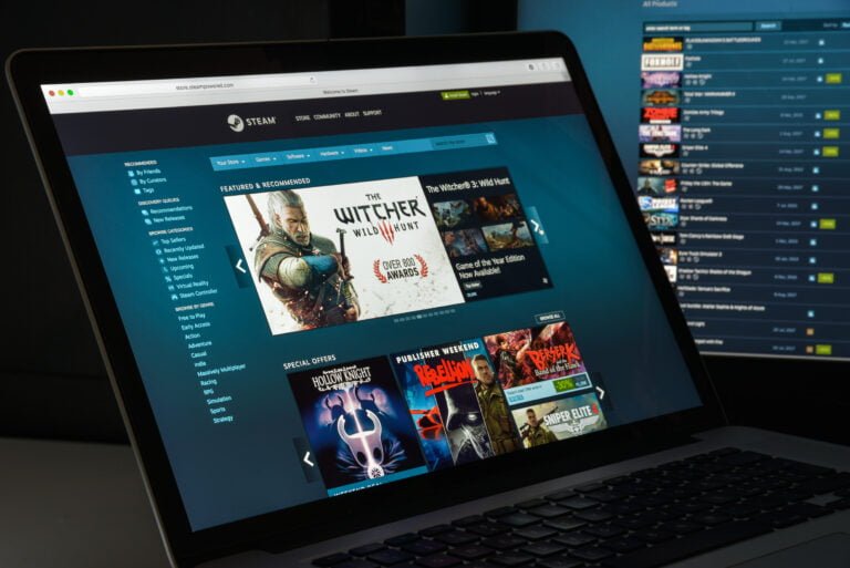Strona główna platformy Steam wyświetlona na ekranie laptopa, z promowanymi grami w tym "The Witcher 3: Wild Hunt".