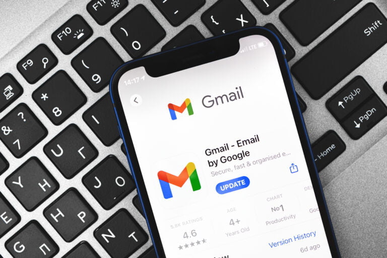 Smartfon z aplikacją Gmail leżący na klawiaturze komputera, pokazuje ekran aktualizacji aplikacji w sklepie z aplikacjami Google Play.