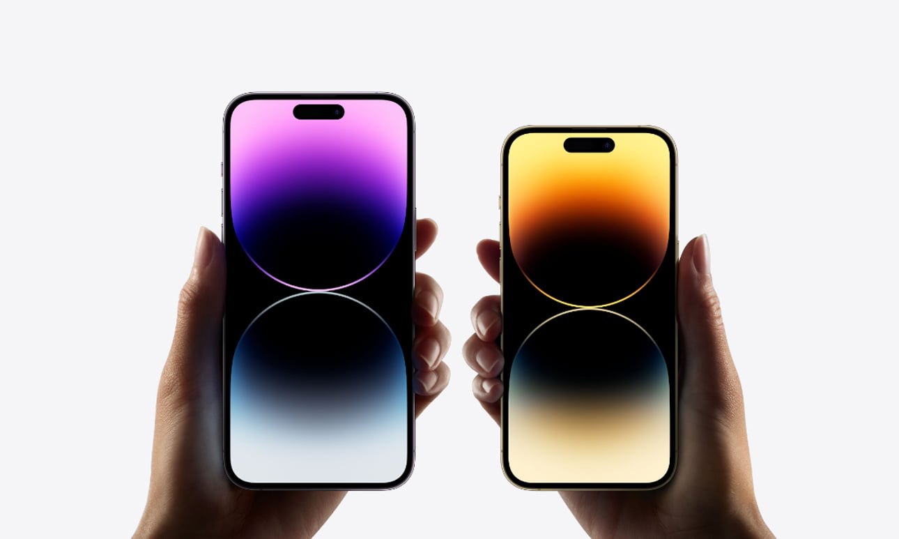 Dwie ręce trzymające dwa smartfony z kolorowymi tłami na wyświetlaczach na białym tle.