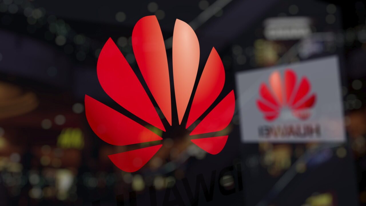 Logo Huawei na pierwszym planie z rozmytymi światłami w tle.