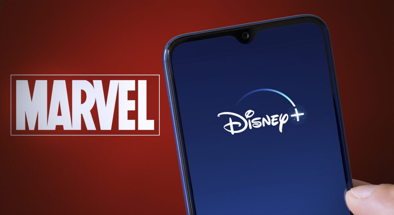 Logo Disney+ wyświetlone na smartfonie. W tle znajduje się logo Marvel na czerwonym tle.