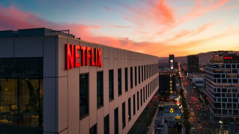 Budynek z logiem Netflix na elewacji. W tle niebo w kolorze pokazującym zachód słońca