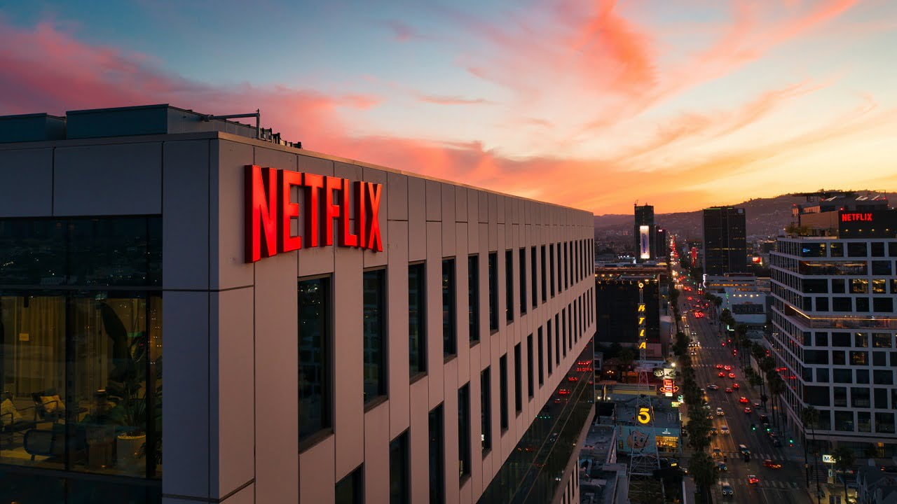 Budynek z logiem Netflix na elewacji. W tle niebo w kolorze pokazującym zachód słońca