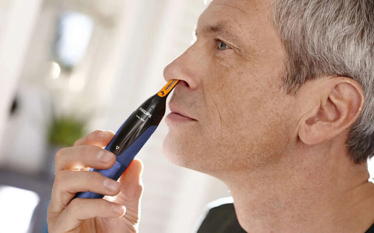 Starszy mężczyzna używa elektrycznego trymera do włosów nosa marki Philips.