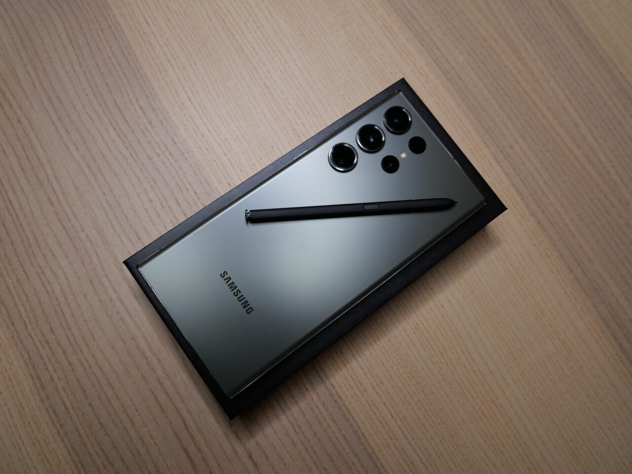 Smartfon Samsung leżący na drewnianym blacie z wyjętym rysikiem S Pen i widocznym modułem pięciu kamer.