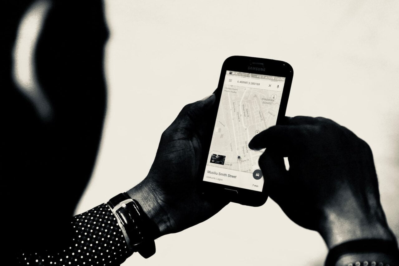 Osoba trzymająca smartfon Samsung i przeglądająca mapę na ekranie, czarno-białe zdjęcie.