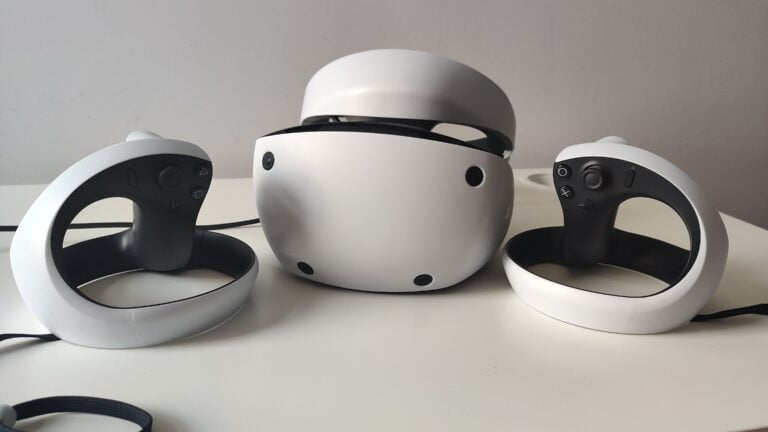 Gogle wirtualnej rzeczywistości marki Sony PlayStation VR2 z dwoma kontrolerami na białym biurku.
