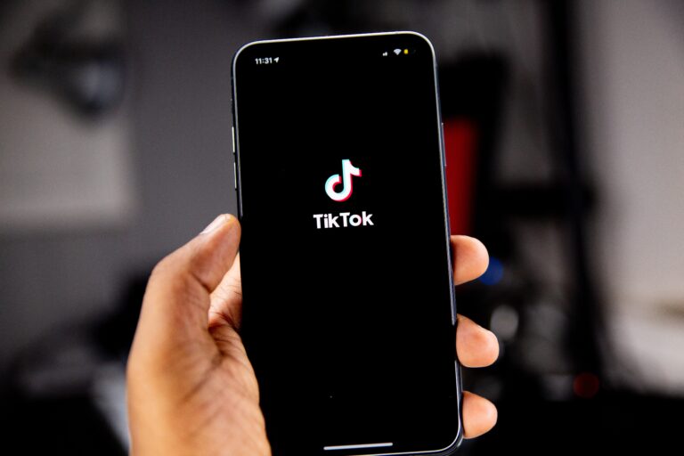 Smartfon trzymany w dłoni z ekranem wyświetlającym logo aplikacji TikTok.