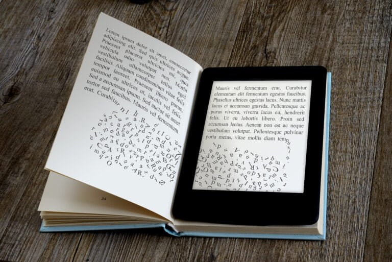 Rozłożona książka i czytnik e-booków na drewnianym stole, z symulacją tekstu "lorem ipsum" na obu stronach, przy czym litery z e-booka "wypadają" na stronę książki.