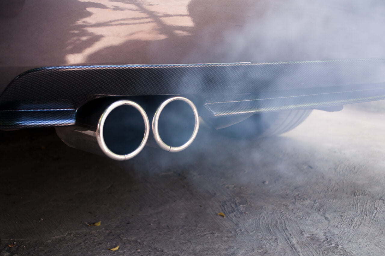 Emisja spalin w UE. Dym wydobywający się z podwójnej końcówki wydechu samochodu. Nie Strefa czystego transportu na to nie pozwoli