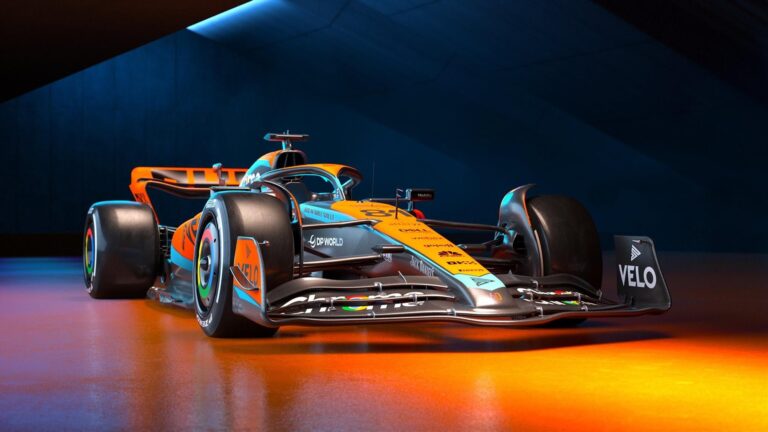 Formuła 1 bolid McLarena zaparkowany na ściance pitstopowej, z efektywnym oświetleniem w tle.