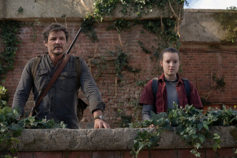 Mężczyzna i dziewczyna za ścianą z cegły, otoczeni roślinnością, z widocznym napięciem na twarzach. Serial The Last of Us - kadr z produkcji