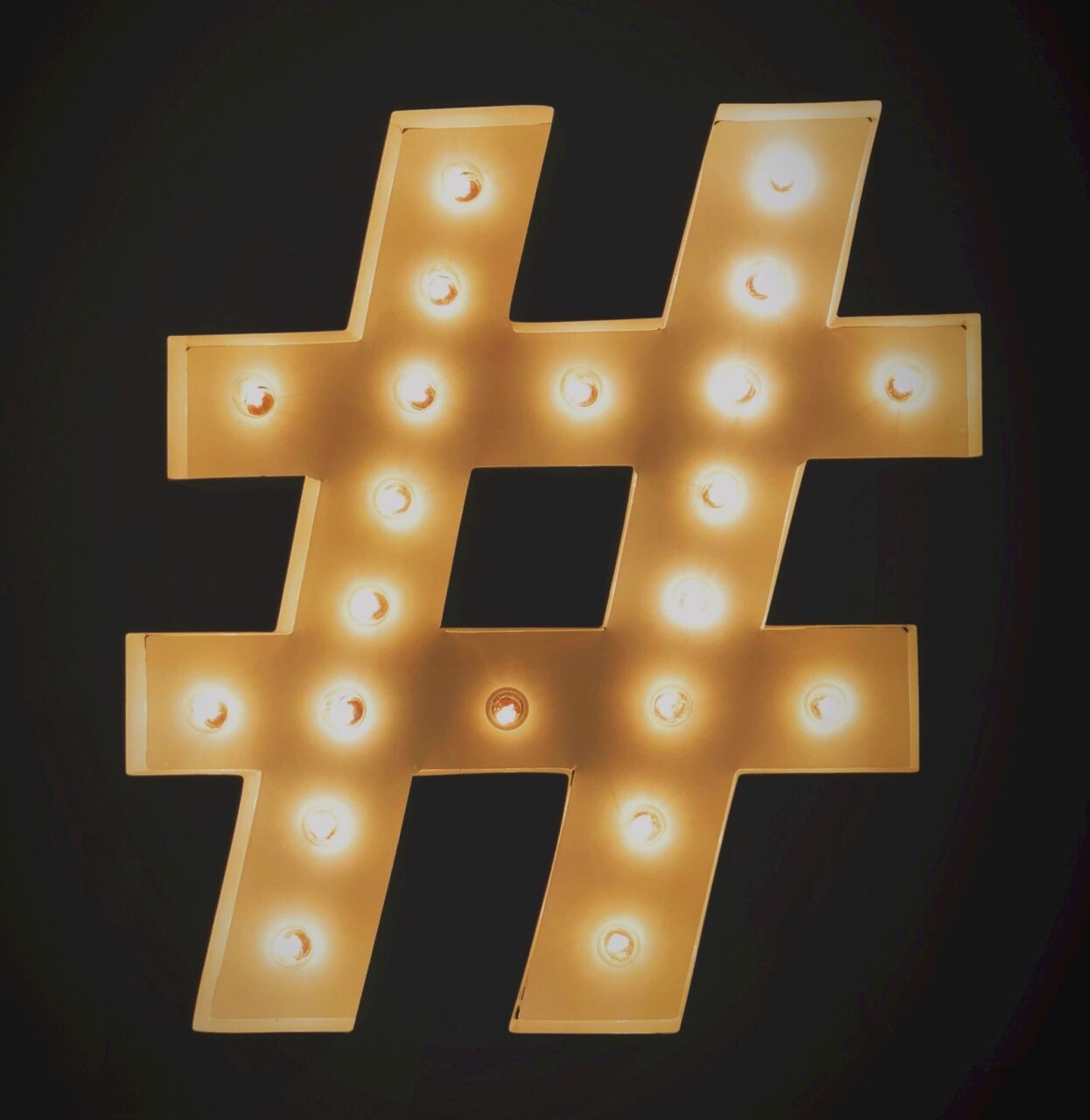 Świecący znak hashtag z żarówkami na ciemnym tle.