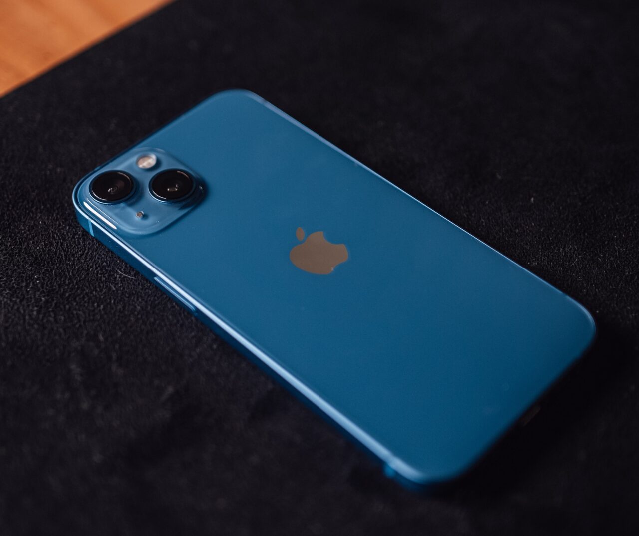 Niebieski iPhone leżący na czarnej powierzchni.