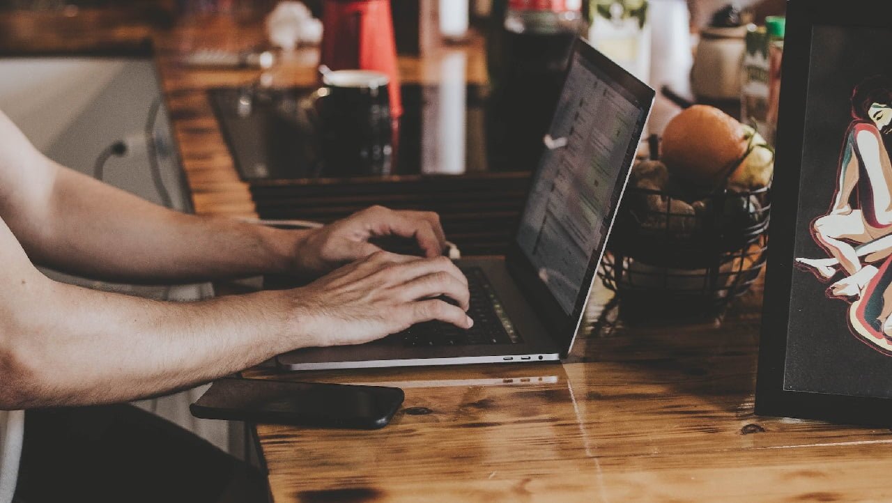 Mężczyzna używający laptopa w kawiarni