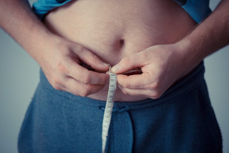 Pandemia XXI wieku - otyłość. Osoba mierzy obwód swojego brzucha taśmą mierniczą.