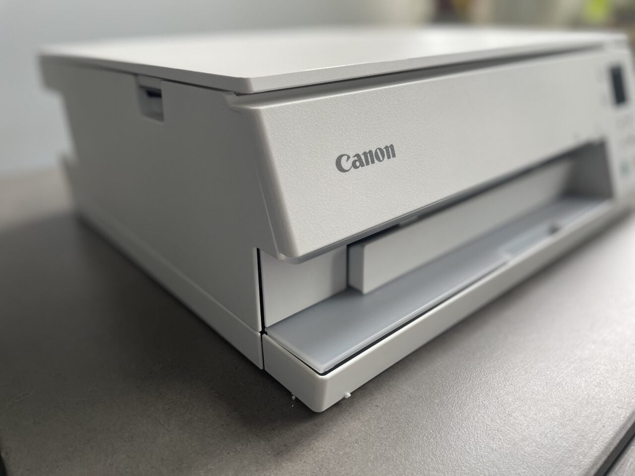 Szara drukarka marki Canon na biurku w zbliżeniu.