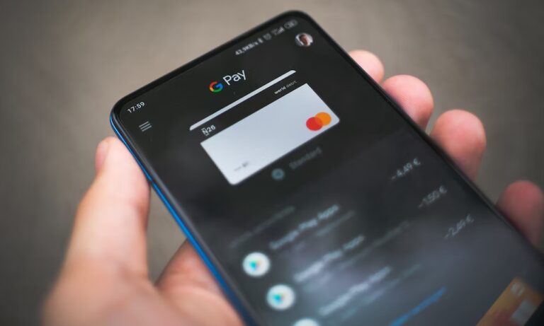Osoba trzymająca smartfon z aplikacją Google Pay NFC wyświetlającą kartę Mastercard.