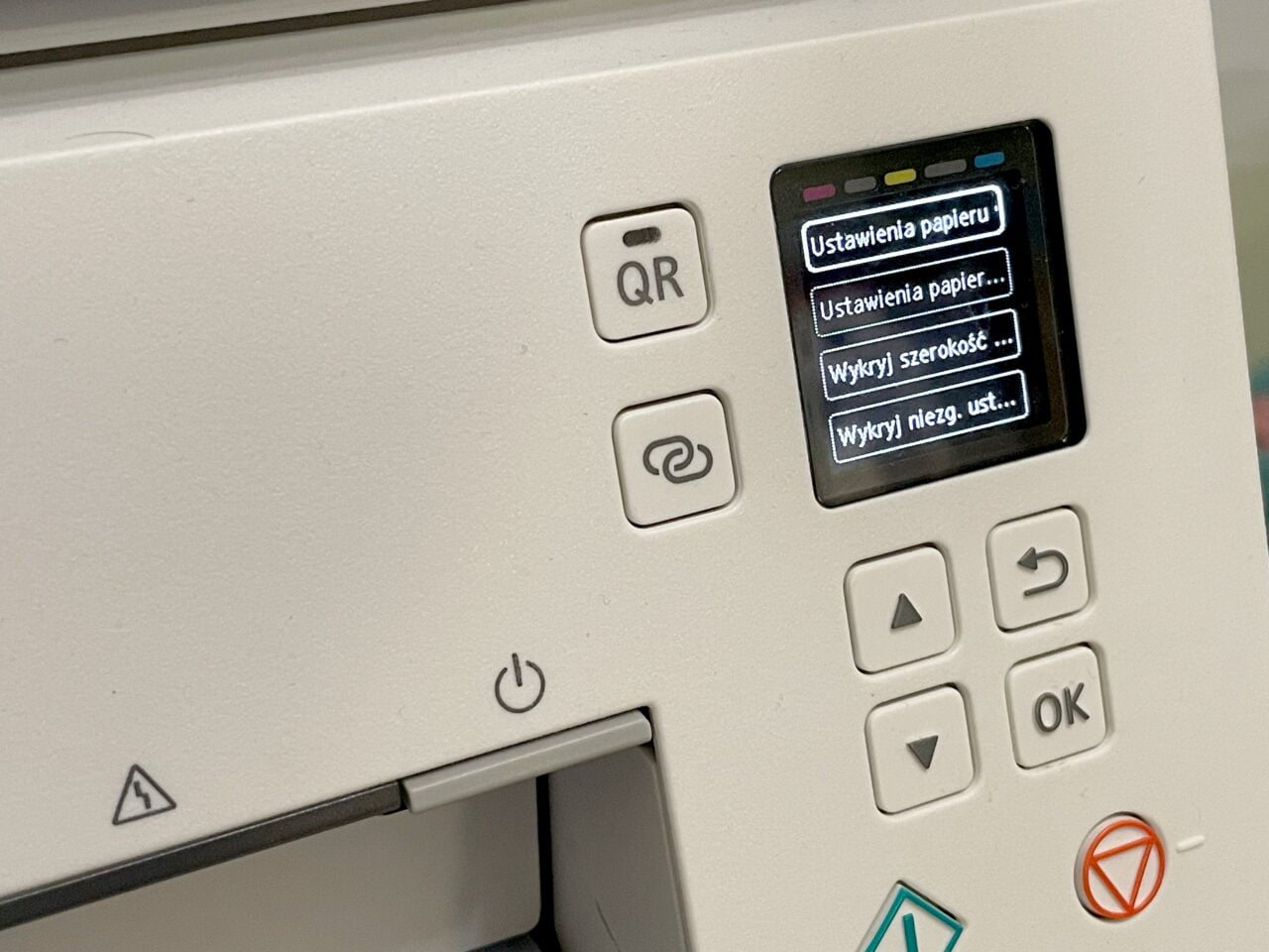 Panel sterowania drukarki z kolorowym ekranem LCD wyświetlającym opcje ustawień papieru oraz przyciskami nawigacji i potwierdzenia (OK).