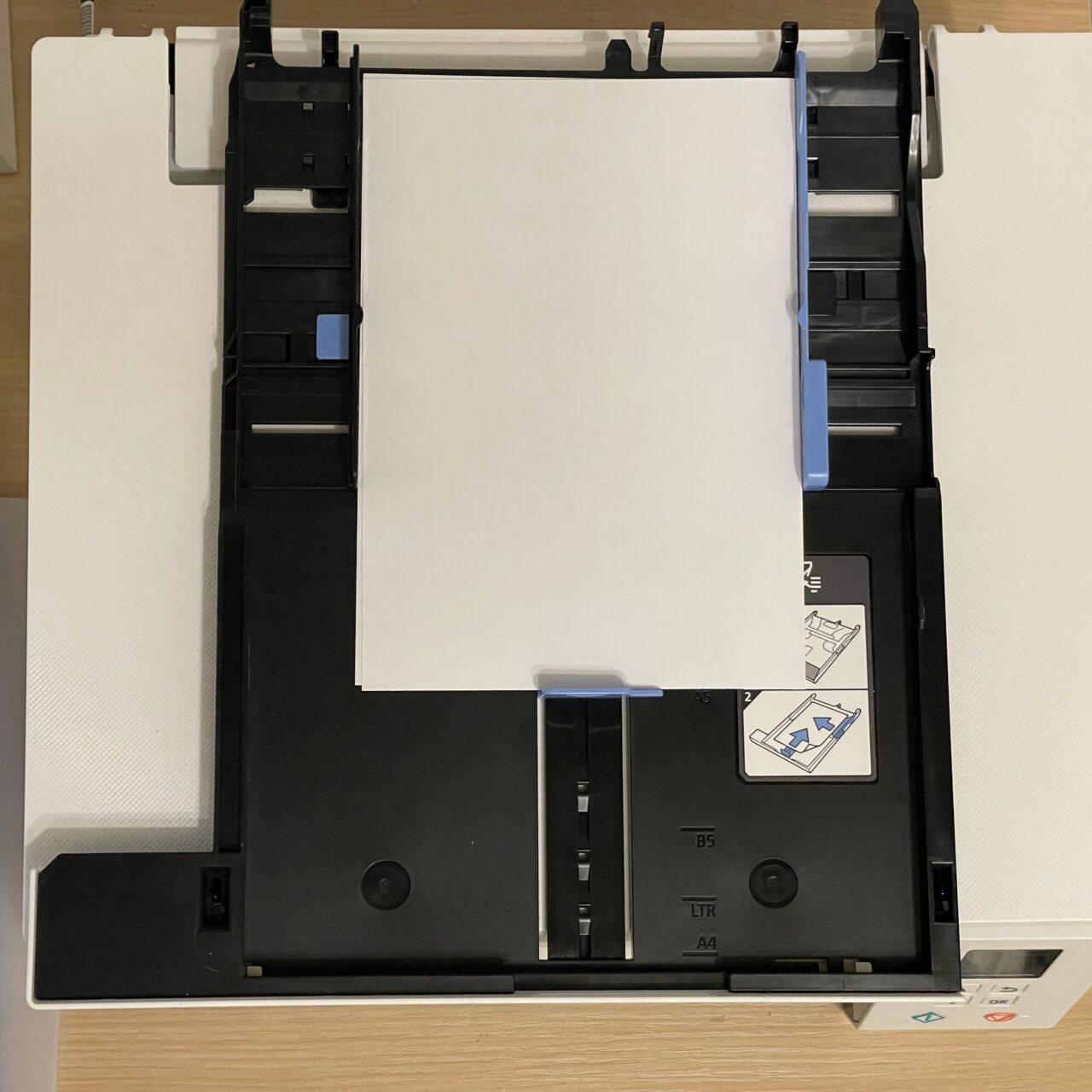 Podajnik papieru drukarki z umieszczonym w nim arkuszem białego papieru formatu A4.