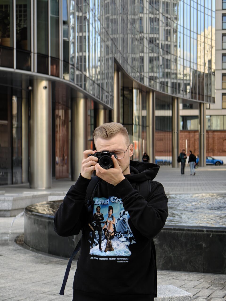 Mężczyzna robiący zdjęcie aparatem fotograficznym na tle nowoczesnych biurowców.