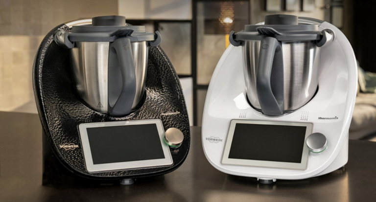 Dwa wielofunkcyjne roboty kuchenne Thermomix 7 na blacie, jeden czarny i jeden biały.