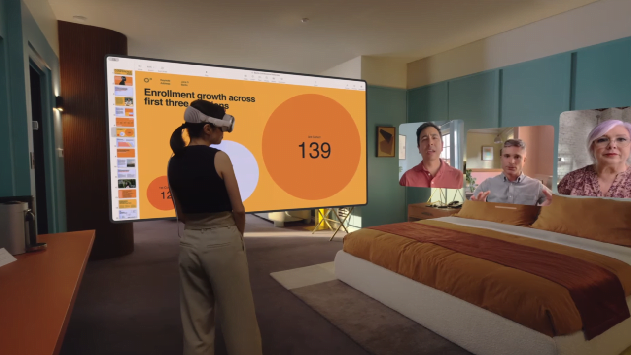 Kobieta w wirtualnej rzeczywistości stoi przed dużym ekranem prezentującym dane, trzy osoby są wyświetlane na wirtualnych panelach z boku ekranu.