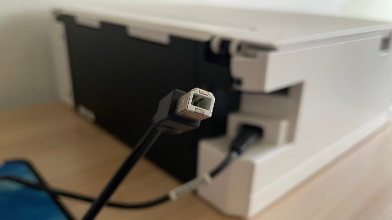 Kabel USB z wystającą wtyczką typu A przed otwartą komorą obudowy komputera, rozmyte tło.