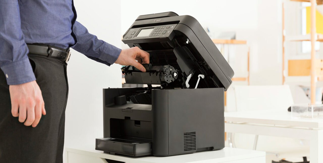 mężczyzna trzymający kasetę z tonerem i montujący ją w drukarce