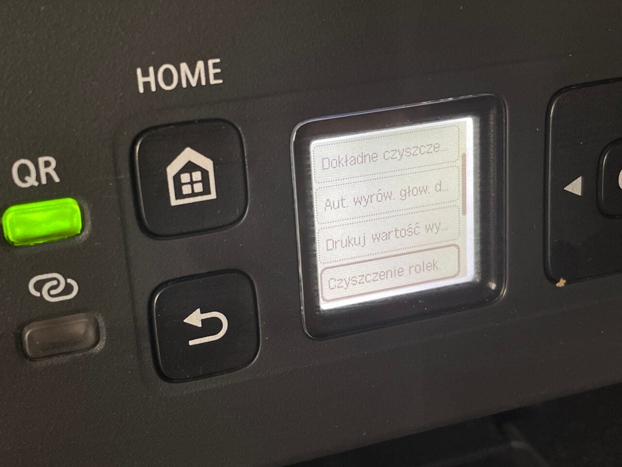 Panel sterowania urządzenia z ekranem LCD wyświetlającym opcje konserwacji, przyciskami nawigacyjnymi i oznaczeniami "HOME" oraz "QR".