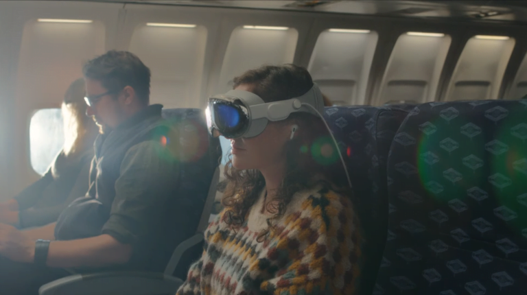 Pasażerka samolotu siedząca przy oknie i nosząca gogle MR Apple Vision Pro, z mężczyzną siedzącym obok, rozmytym w tle.