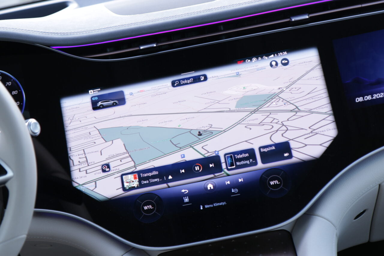 Ekran systemu nawigacji w samochodzie wyświetlający mapę i interfejs użytkownika z ikonami funkcji takimi jak telefon czy muzyka.