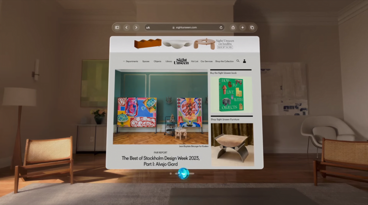 Ekran komputera Apple Vision Pro pokazujący stronę internetową z artykułami o designie, umieszczony w nowocześnie urządzonym pokoju.